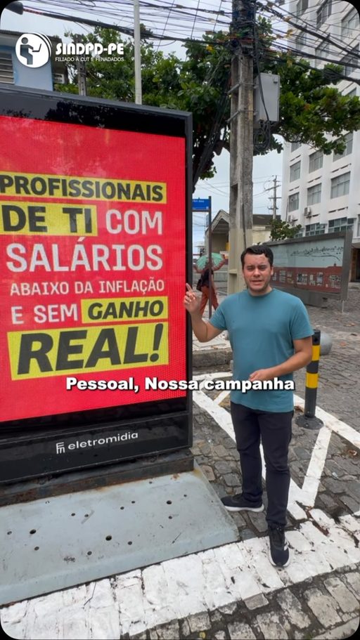 Vídeo de Reinaldo ao lado de painel da campanha: profissionais de TI com salários abaixo da inflação e sem ganho real